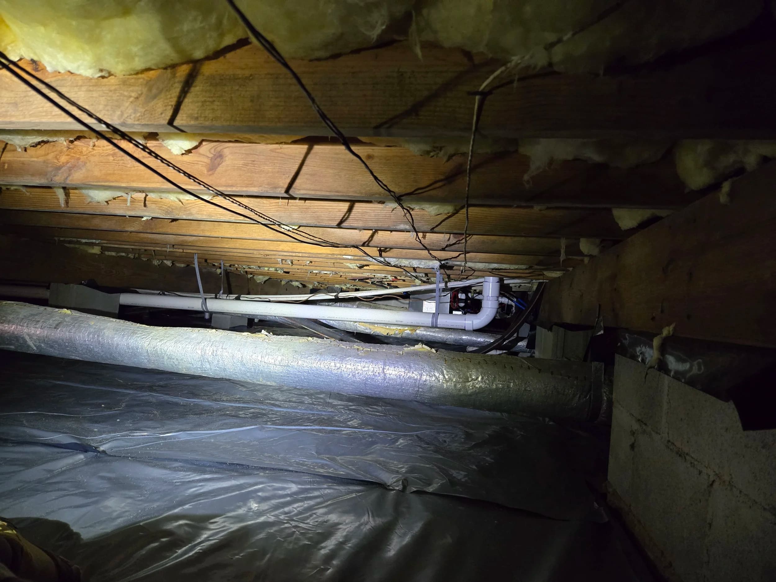 Beneath a Central Virginia home: insulation, vapor barrier, and supply lines under the joists